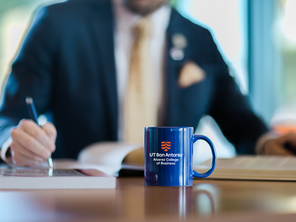 Man in suit writing with coffee mug in foreground