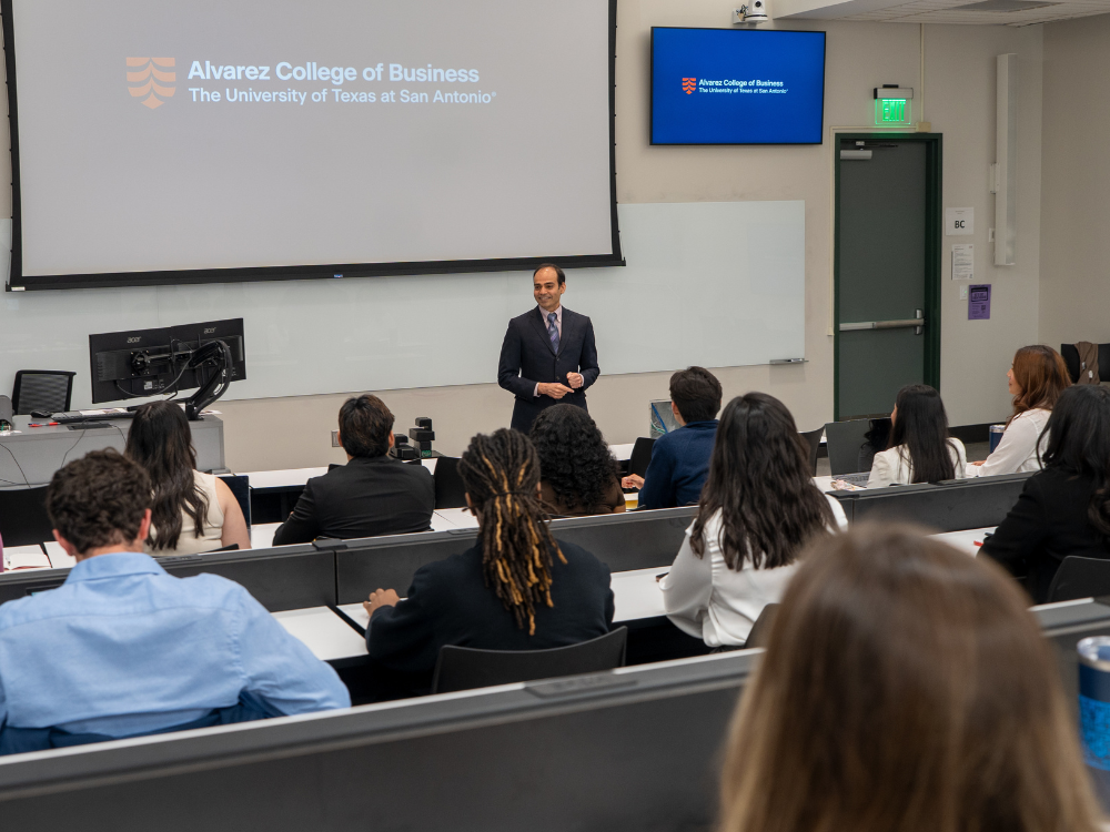 Professor in suit speaking to classroom of students.