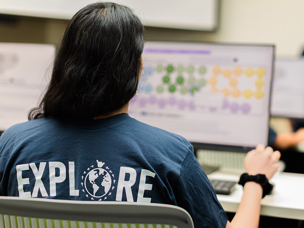 Image of girl at computer with "Explore" on back of shirt