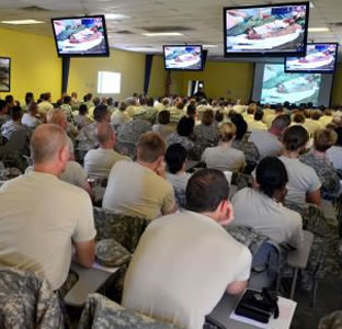 Photo of classroom with soldiers at desks and images on screens overhead.