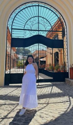 Image of Jasmine Mendoza in front of a large iron gate.