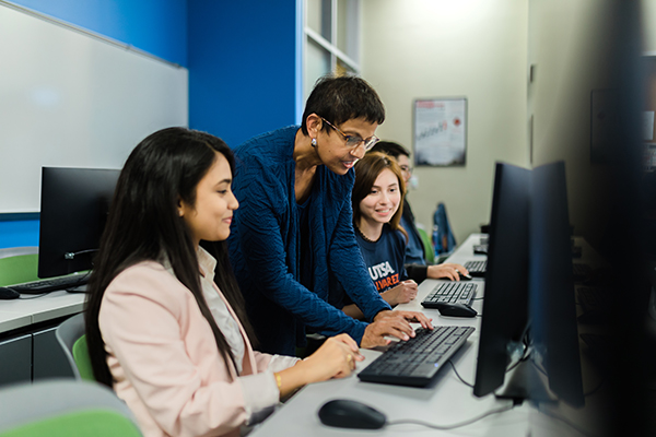 Photo of professor in classroom with students at computer.