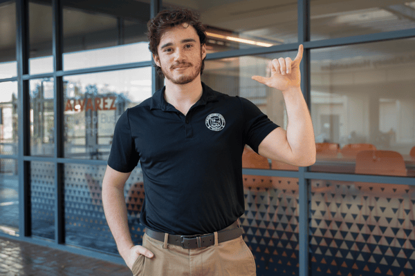 BBA Finance graduate Carson Cowan poses with "Birds Up" hand sign.