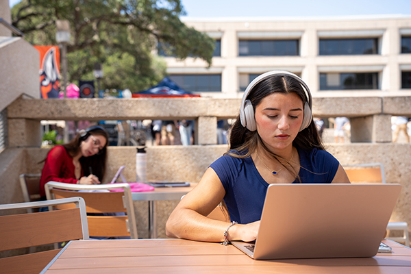 Student studying outside on a computer.